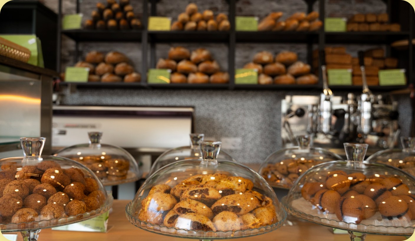 A bakery display case filled with doughnuts and pastries under glass domes.