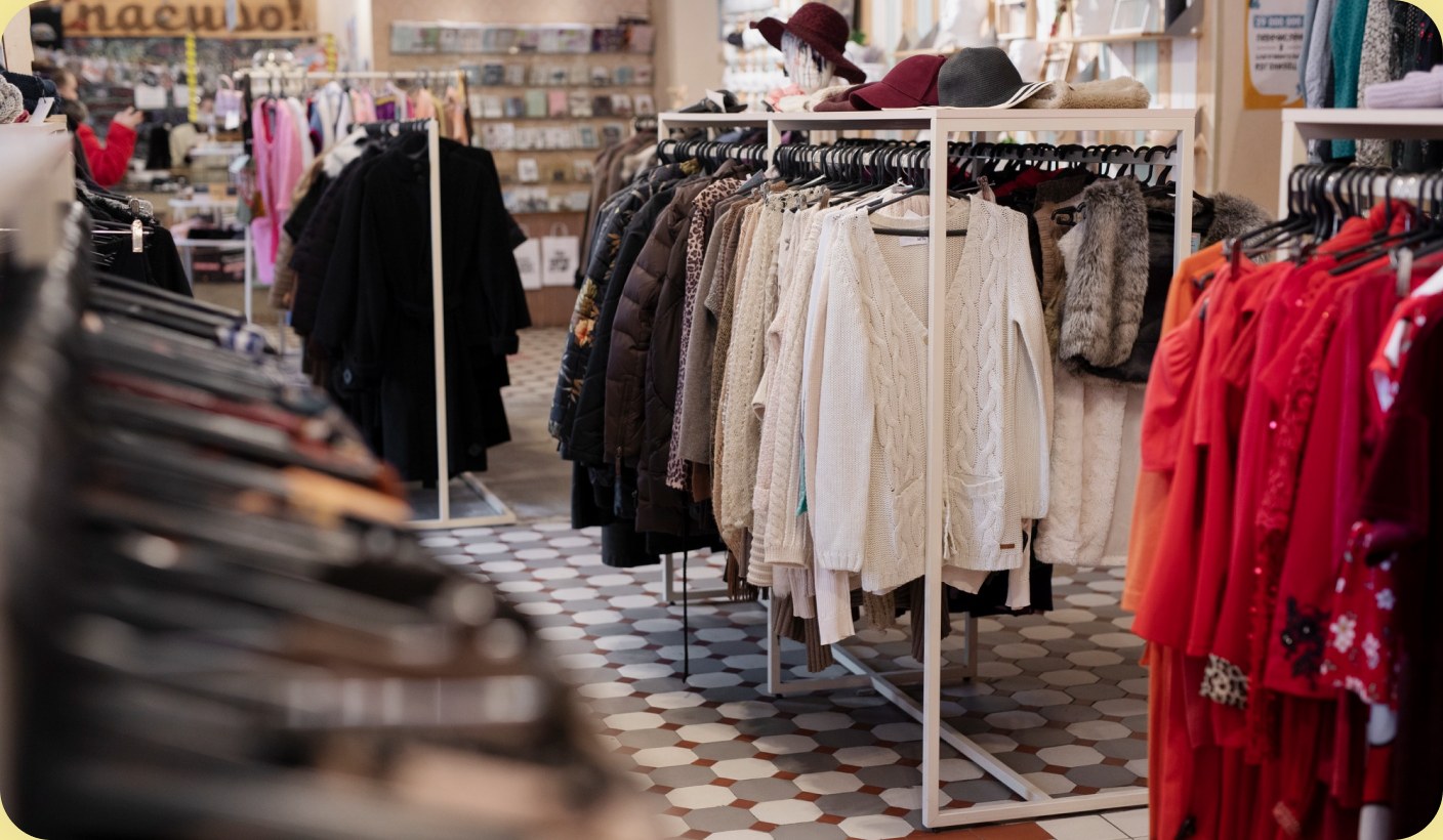 Rails of clothing in a boutique, with a patterned tiled floor.