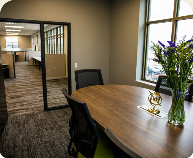 A dedicated-desk area beyond a glass door, with a wooden table and a vase of irises.