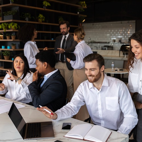 A group of people talking around a table at a CMURC networking event in a bright plant-filled space.