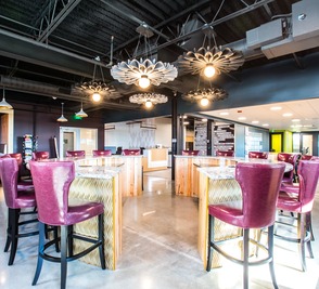 A CMURC café lounge with magenta velvet armchairs and sputnik chandeliers.