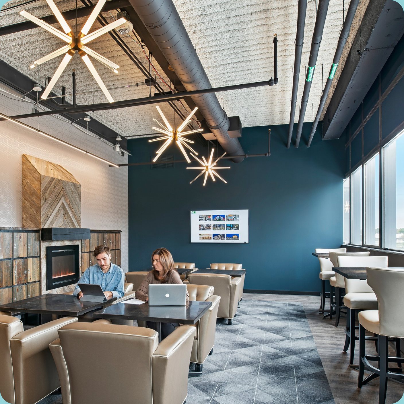 CMURC lounge with starburst pendant lights, leather armchairs and two members working at a table.