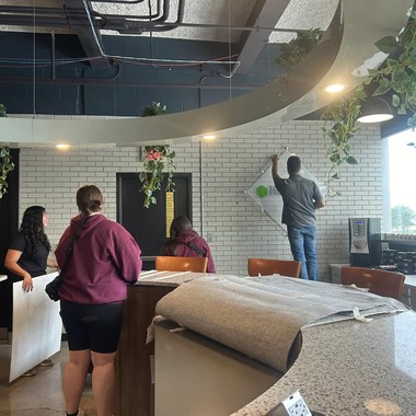 Visitors talking in the CMURC lobby beside a curved white brick wall hung with plants.