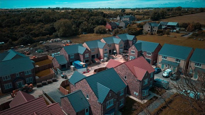 An aerial view of a new-build housing estate with pitched roofs.