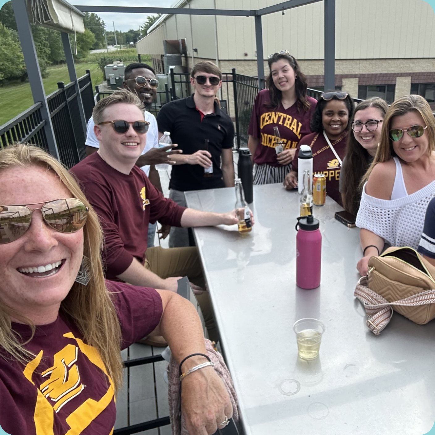 CMURC team members gathered around an outdoor table, wearing Central Michigan maroon.